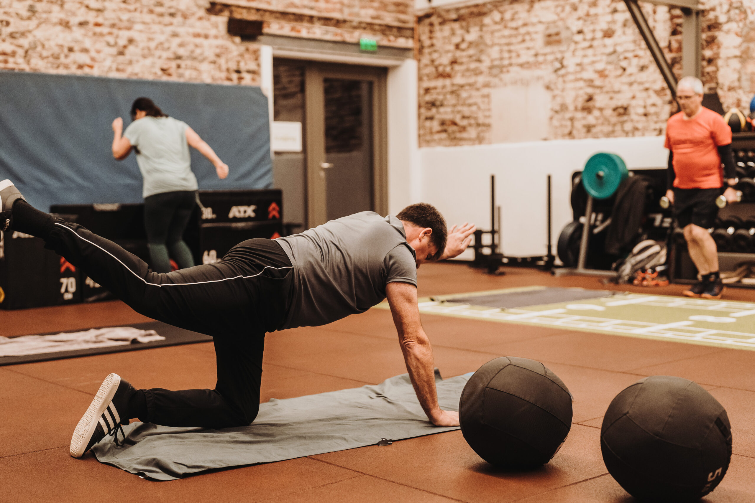 Mann beim Fünfzig Plus Training macht Übung neben Medizinbällen